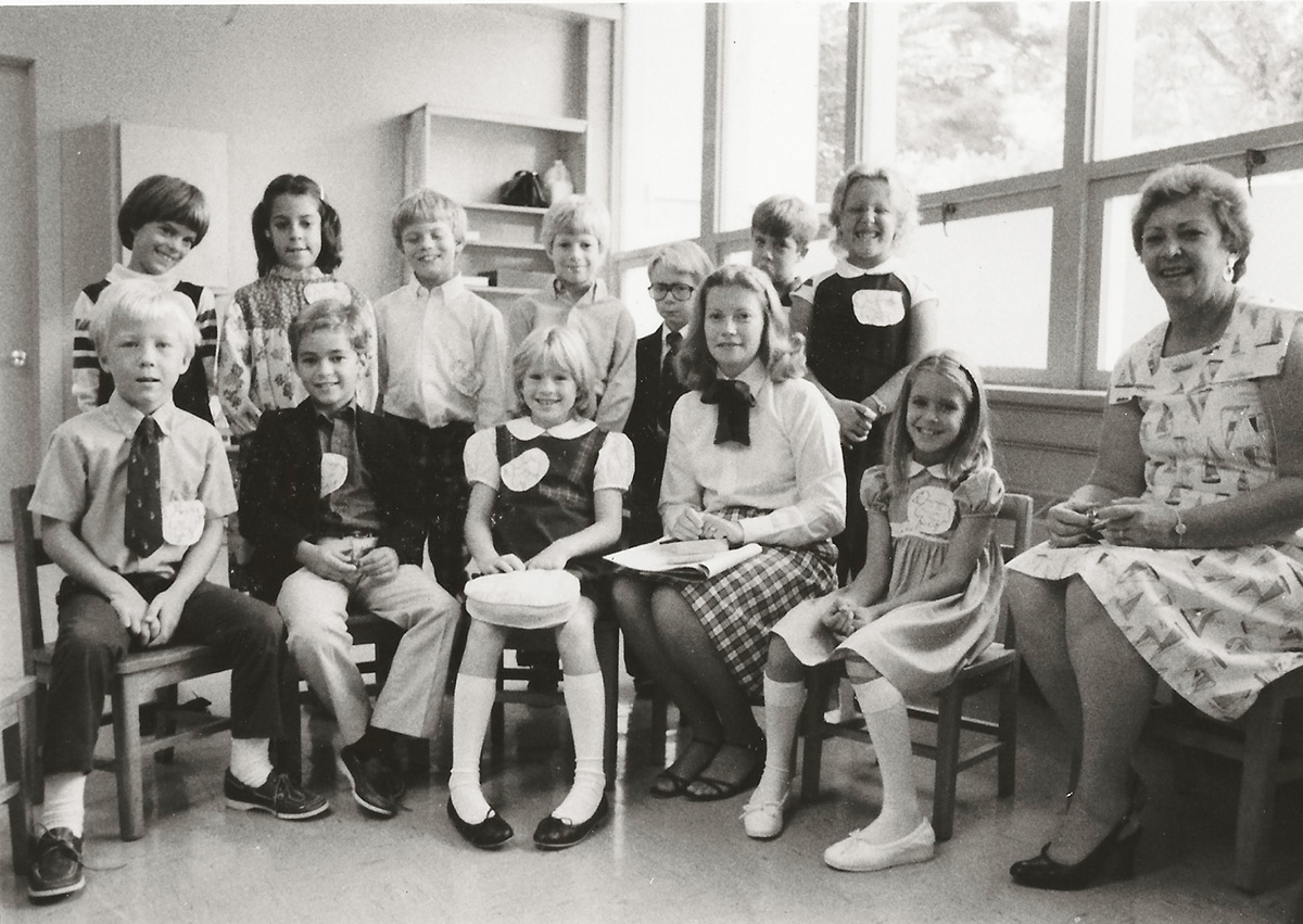Children and two adult women pose together in a classroom.