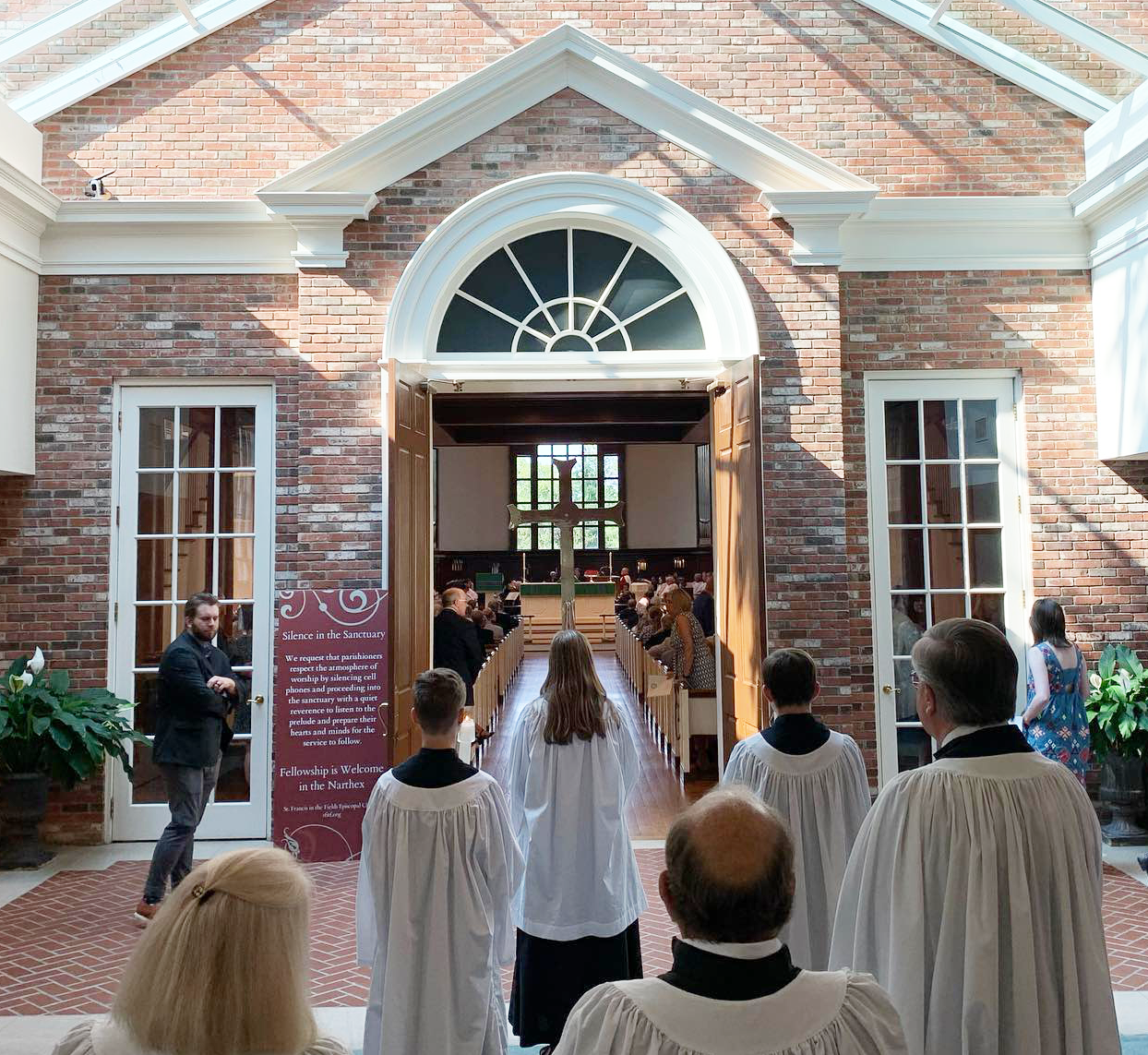 Acolytes process through open doors into the nave for worship.