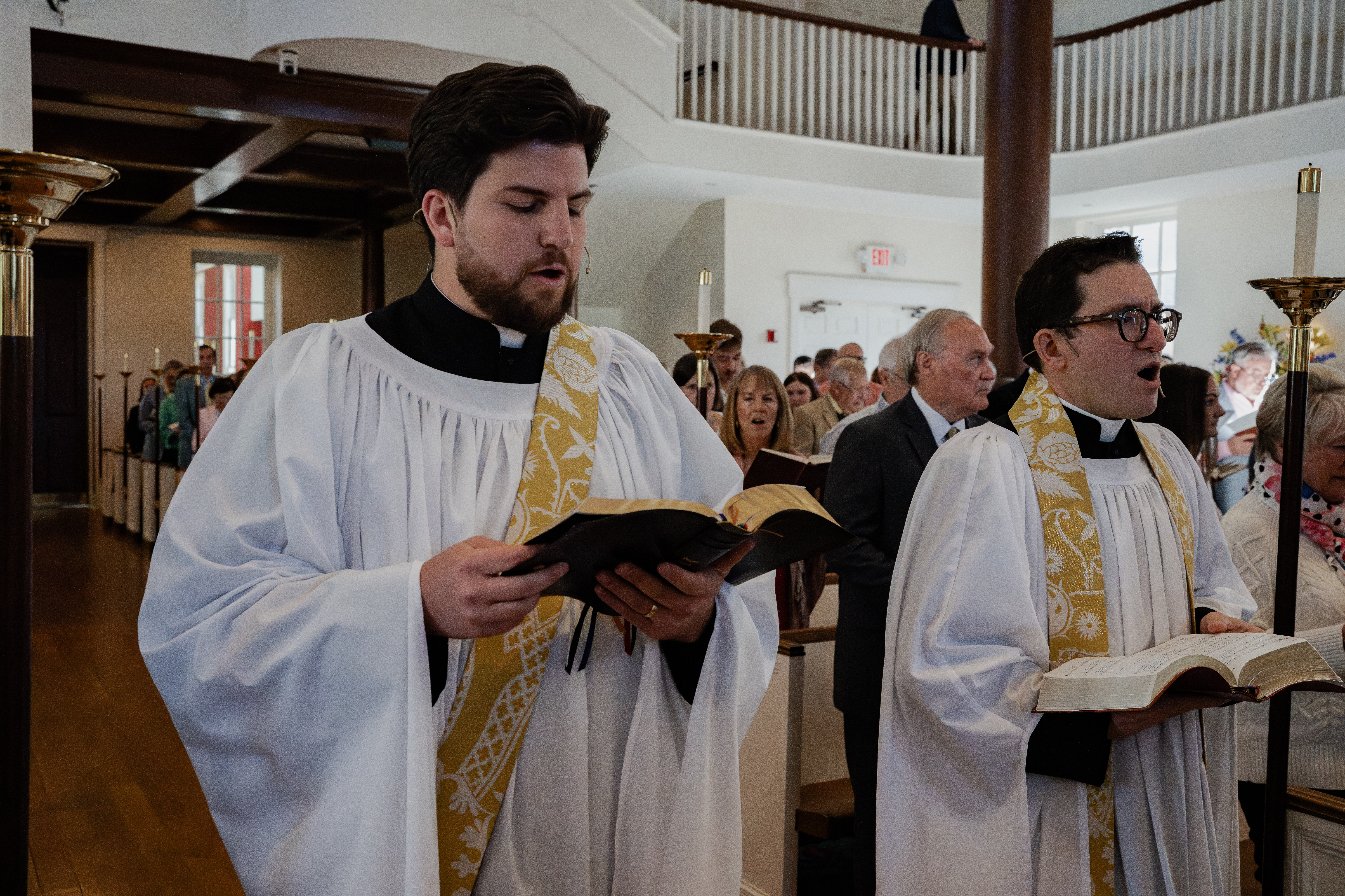Two clergy members sing a hymn
