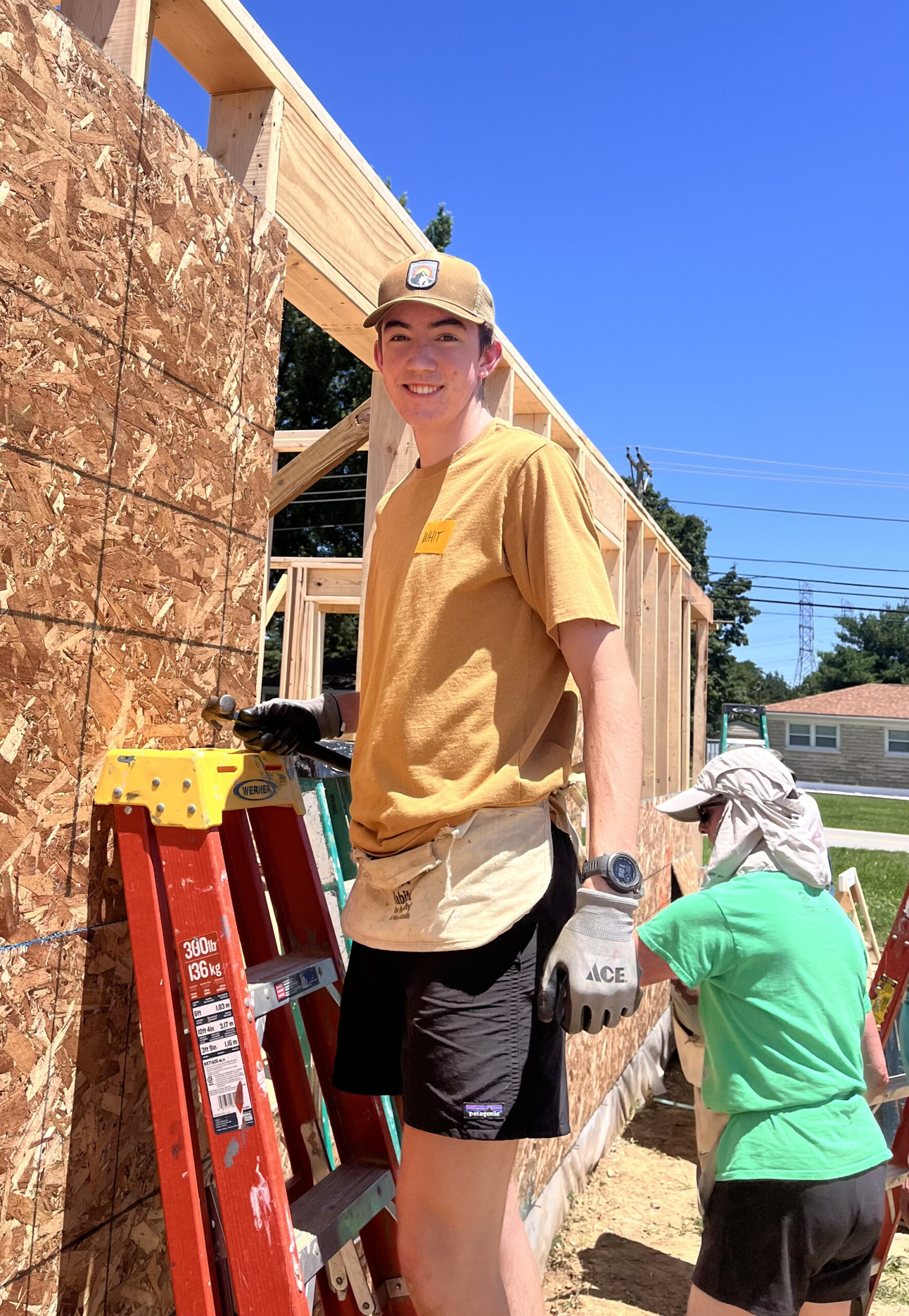 A young man stands on a ladder at a construction site.